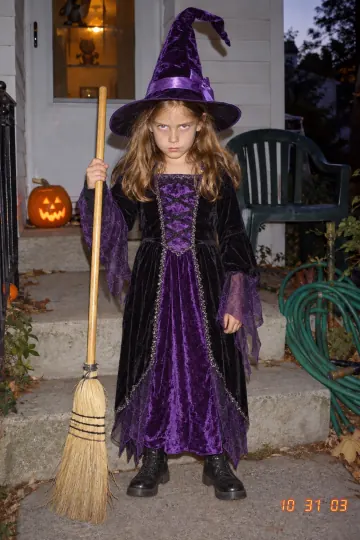 A girl in a purple velvet witch costume on Halloween night